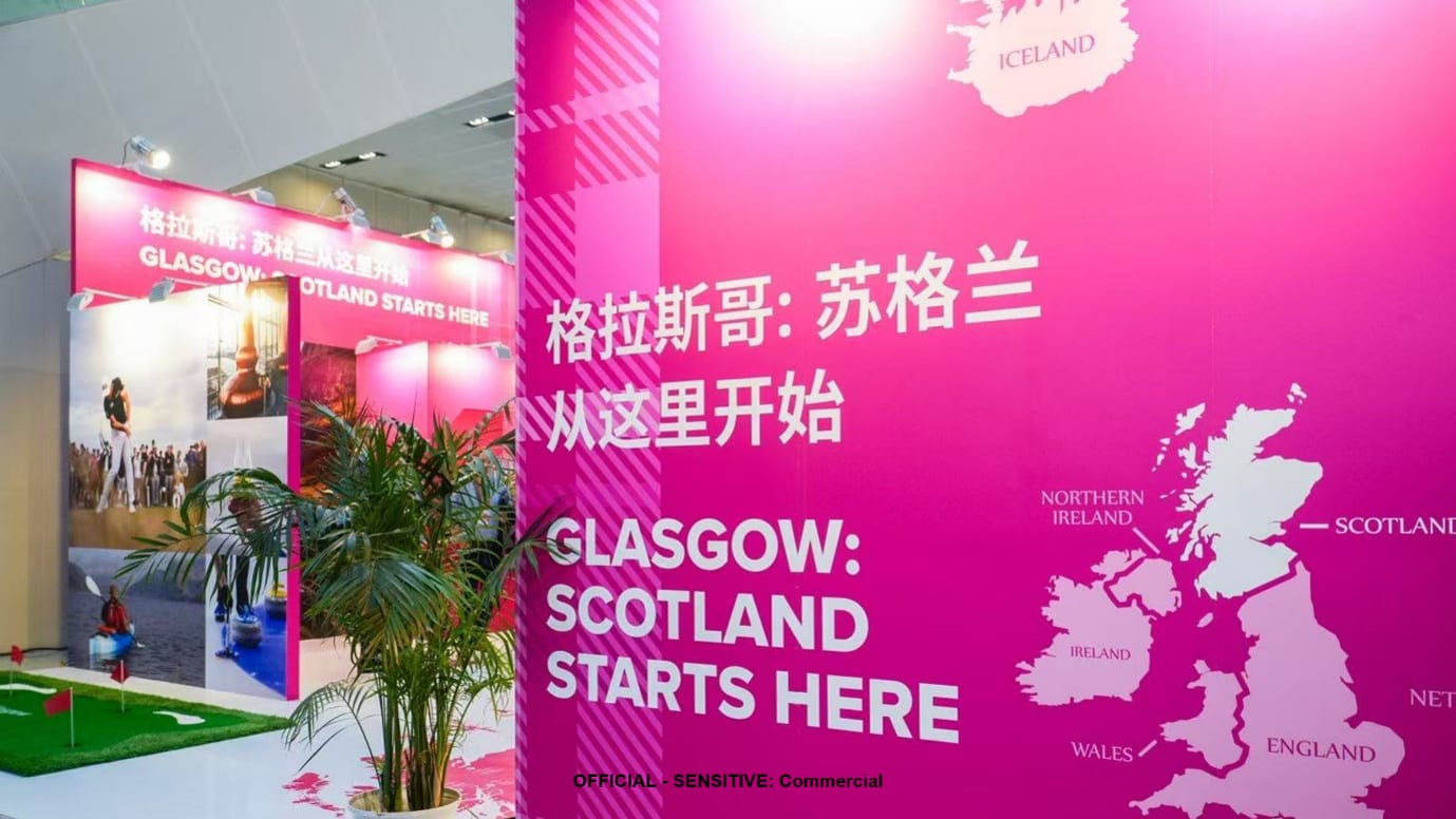 A shot of an Expo display. The banners have a hot pink tartan background. On top of the banner is the text 'Glasgow: Scotland starts here' in English and Mandarin, with a map of the UK highlighting where Scotland is.